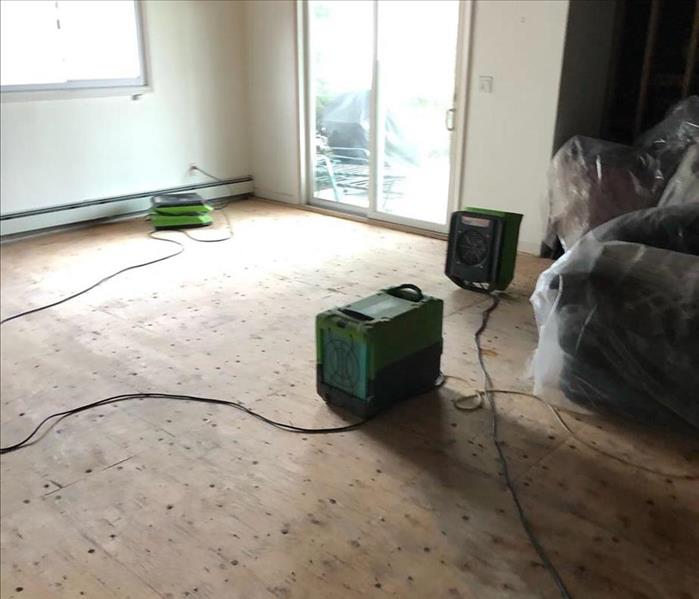 Room with an exposed subfloor and SERVPRO equipment
